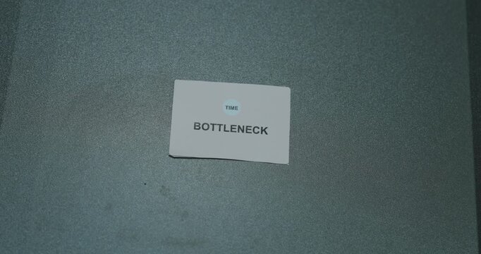 Bottleneck text on a white paper card against a gray background, representing workflow constraints and business efficiency