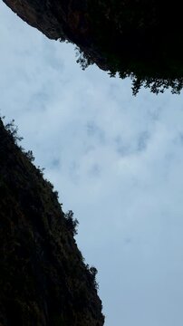 Low angle timelapse shot of grey clouds moving fast over the steep cliffs of Presa de Isber gorge in Alicante province, Spain.