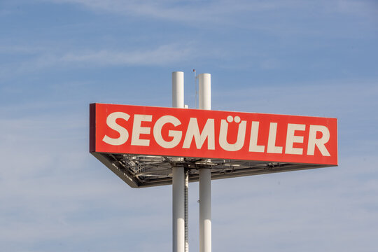 Deutschland &ndash; Gro&szlig;er Werbeturm und Werbeschild mit dem roten Firmenlogo des M&ouml;belhauses Segm&uuml;ller vor blauem Himmel.