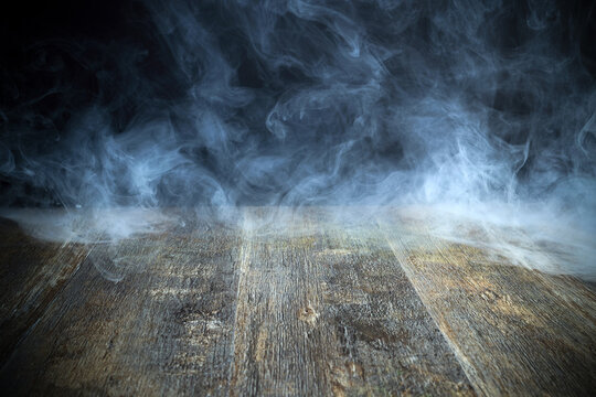 Smoke swirling on dark wooden surface creating mystery