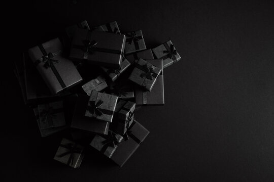 Black gift boxes with ribbon bows on dark background