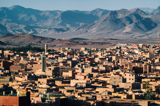 Tinghir, morocco city panorama featuring traditional adobe architecture, a prominent minaret, and the high atlas mountains in background