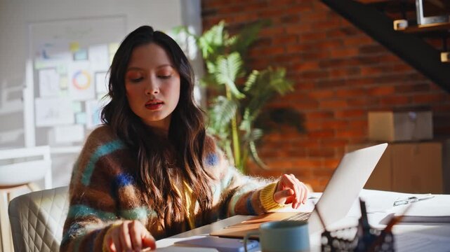 Entrepreneur writing notes laptop loft office. Asian business woman notebook.