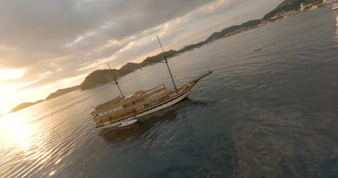 FPV aerial view of traditional wooden phinisi boats anchored in the calm waters of the bay at Labuan Bajo, Komodo, East Nusa Tenggara, Indonesia.