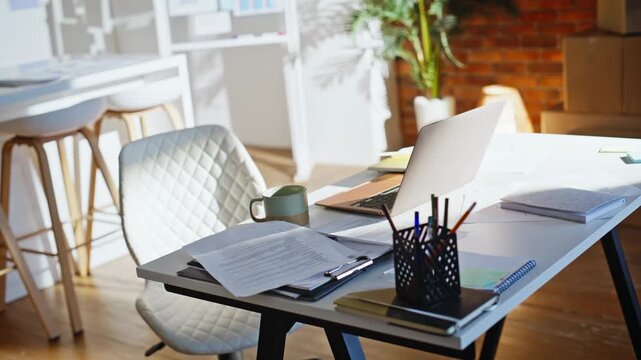 Modern work place laptop documents coffee mug. Loft office interior no people.