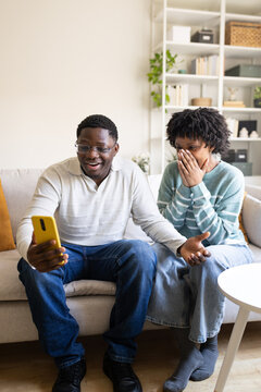 Excited couple sharing surprising news on smartphone at home