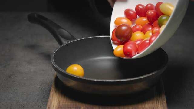 Tomatoes, garlic, and thyme are placed in pan on wooden cutting board set on black tabletop. Preparation of Italian tomato and ricotta bread; close-up of the food.