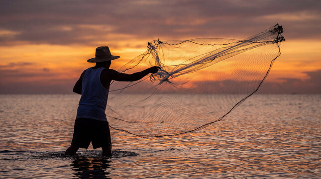 A fisherman wearing a straw hat casts a traditional fishing net into the ocean during a vibrant golden sunset, creating a beautiful silhouette.