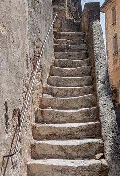 Alte Steintreppe mit verwitterten, ausgetretenen Stufen und einem Gel&auml;nder an einer Steinmauer, Provence, Frankreich