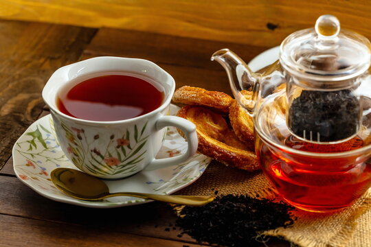T&egrave; nero con teiera di vetro , tazza con piattino e pasticcini