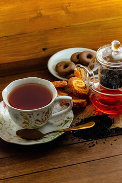 T&egrave; nero con teiera di vetro , tazza con piattino e pasticcini