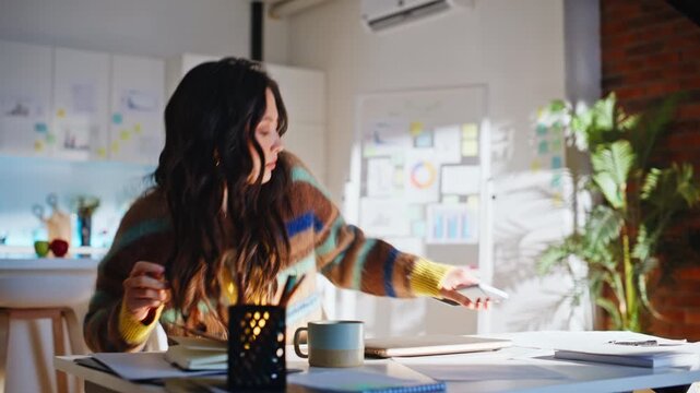 Asian woman sitting desk opening laptop. Designer starting workday home office.