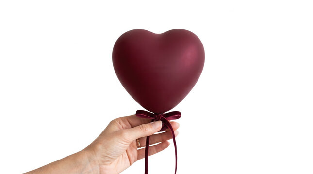 A hand elegantly holds a deep burgundy heart-shaped balloon tied with a satin ribbon, set against a stark black background, symbolizing love and affection in a minimalist style