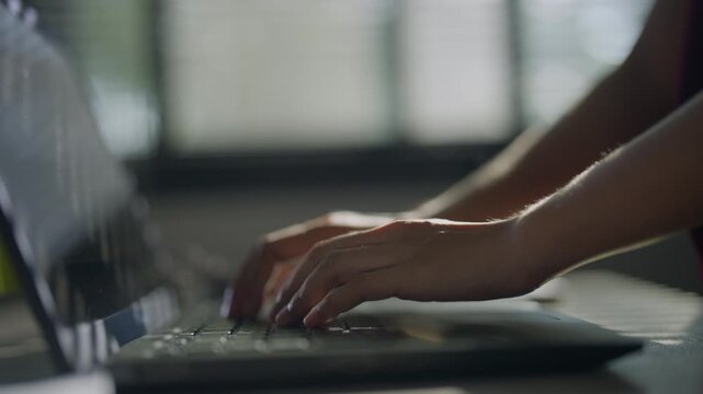 Close-up side view of a hand typing on a computer keyboard in a dark workspace, representing digital work, technology, data entry, online communication, productivity, and modern office tasks.