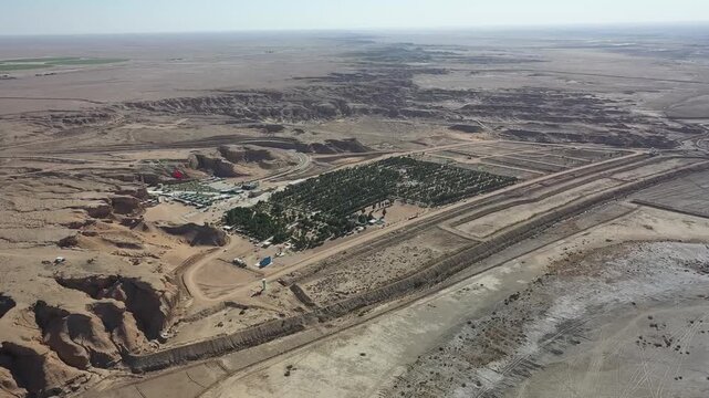Slow aerial pan over a green palm grove oasis among desert canyons near Karbala, Iraq