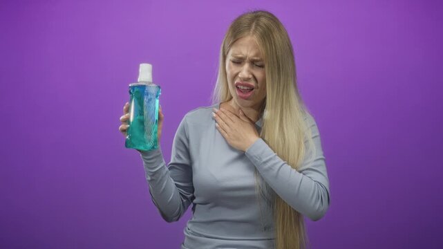 Woman holding a bottle of mouthwash, coughing into a fist and clutching her throat in studio; disgust.