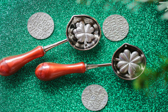 Tin Pouring Set on Green Glitter Background for ,holiday gift sets and New Year fortune telling activities.New Year Tin Pouring Set with Green Glitter Copy Space. 