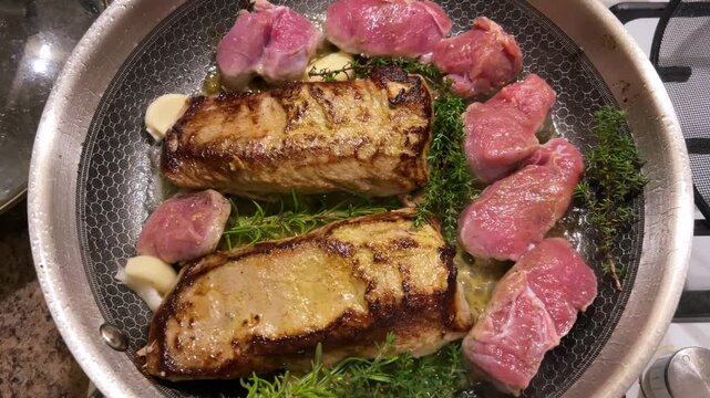 Juicy veal steaks and tender medallions are seared with aromatic thyme and fresh garlic in a hot pan, forming a golden brown crust as fresh herbs and butter sizzle.