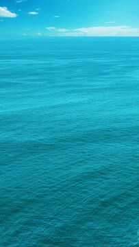 Vast tranquil ocean under a clear blue sky, capturing the endless horizon and peaceful seascape of turquoise waters perfect for travel and vacation concepts. Nature, natural, or quotes background