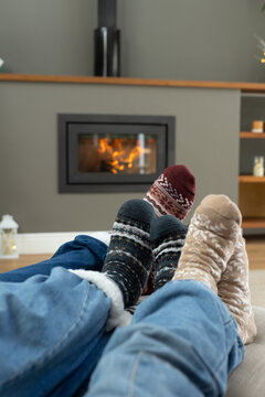African family with teenage daughter warming feet in patterned socks by wood-burning stove at home