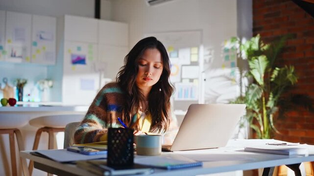 Startup founder writing notes working laptop. Woman planning tasks home office.