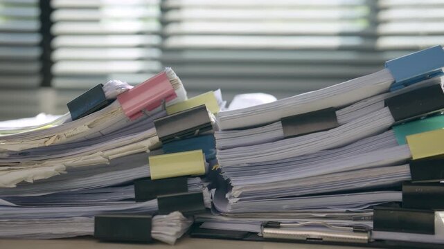Law office professional managing a large stack of legal paperwork and case files, representing heavy workload, document review, case management, legal administration, research, and professional servic