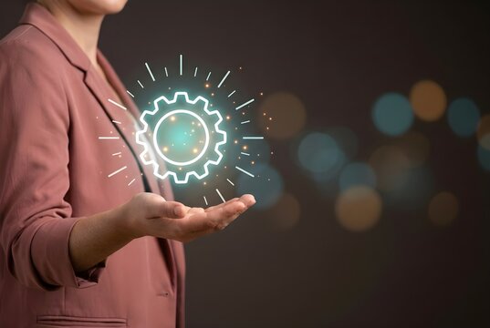 Businesswoman holding glowing gear icon in open hand representing management and strategy