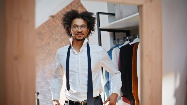 Smiling shopper walking clothing store fitting room. Man untied tie white shirt.