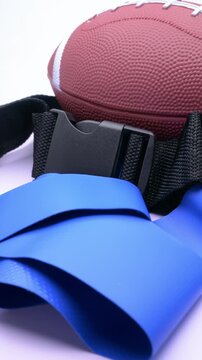 Flag football gear set with american football and blue flag belts rotating at vertical composition