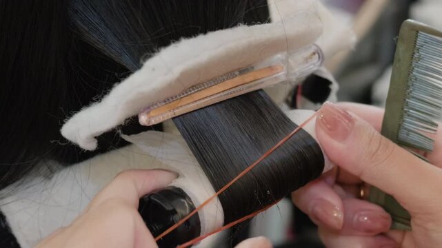 Hairdresser securing a perm rod with an elastic band