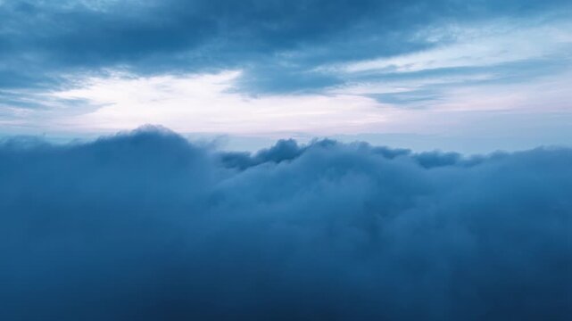 Dramatic aerial view of thick blue clouds gathering in the sky, creating a serene and misty atmosphere during twilight hours.