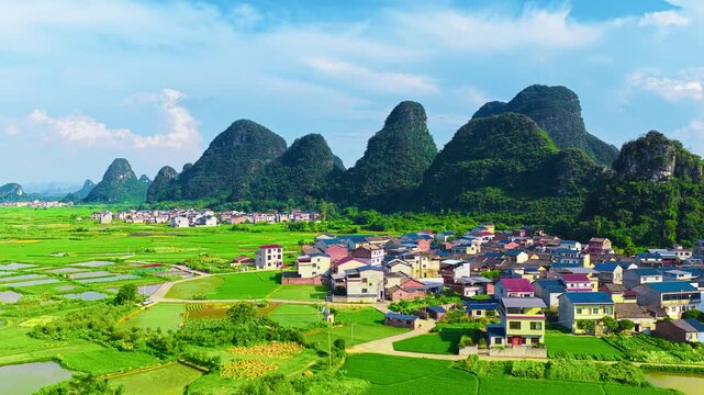 High angle view of Huixian glass paddy fields in Guilin, showing traditional rural houses amidst lush green crops and karst mountains.