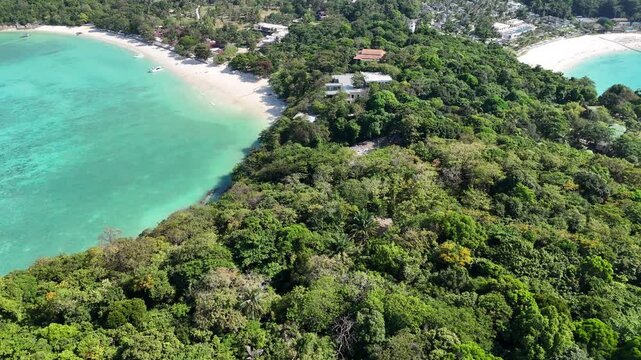 Aerial view of a green forested headland between two crescent white sand beaches with turquoise water in Racha Island Phuket Thailand