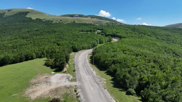 Aerial flight above a gravel road winding through dense green forest to highland meadows in Samsun Turkey