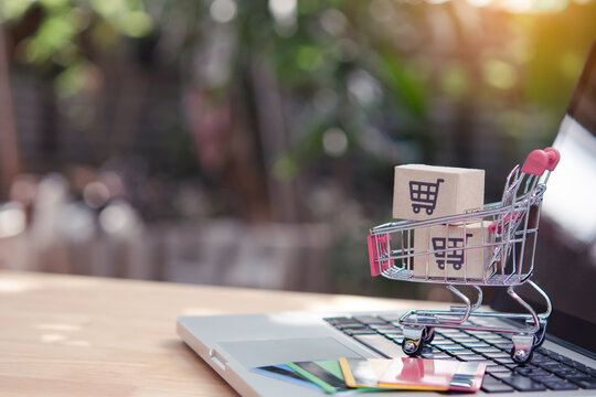 Shopping online. Credit card and cardboard box with a shopping cart logo in a trolley on laptop keyboard. Shopping service on The online web. offers home delivery