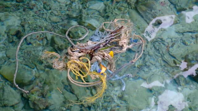 Tangled fishing boat rope trash debris floating in crystal clear ocean water over coral reef environment on tropical island in Indonesia