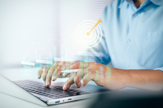 Businessman typing on a laptop with digital target and business growth charts on white desk, concept of corporate goal achievement, strategic planning, and performance analytics