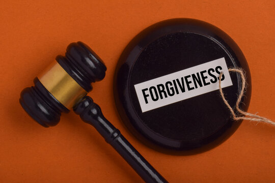 Forgiveness concept represented by a judge's gavel and a labeled legal symbol, illustrating mercy, pardon, reconciliation, and compassionate justice.