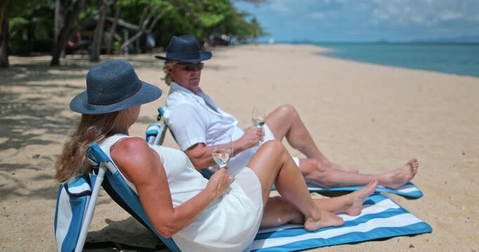 Mature couple relaxing on tropical beach in Thailand, enjoying a luxury resort vacation with drinks, symbolizing retirement, relax and a serene lifestyle by the sea. Ko Samui island travel destination