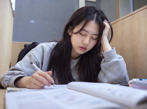 Tired student with closed eyes while studying at a study cubicle