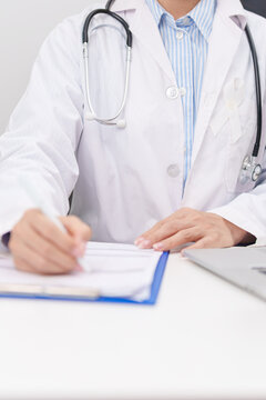 Professional doctor wearing lab coat using laptop and taking report notes on notebook for November Lung Cancer Awareness month, World Cancer Day and oncology healthcare concept in hospital