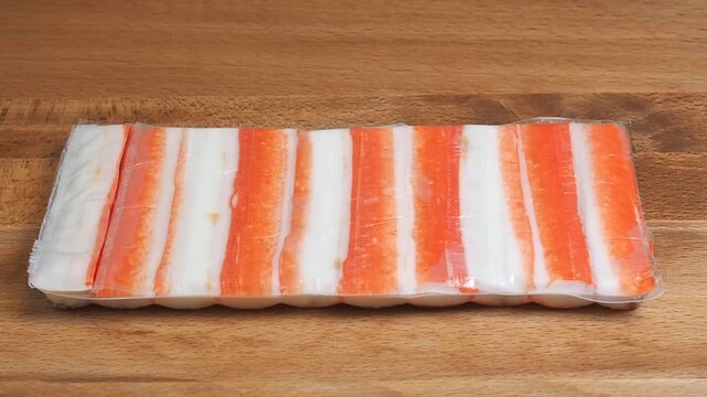 Crab sticks in packaging are placed on a wooden table. Fish delicacies for cooking a dish. Close-up