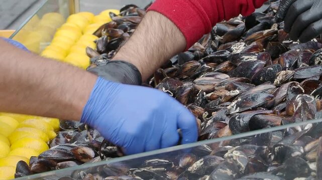 People handling shellfish at a market with fresh lemons in a display