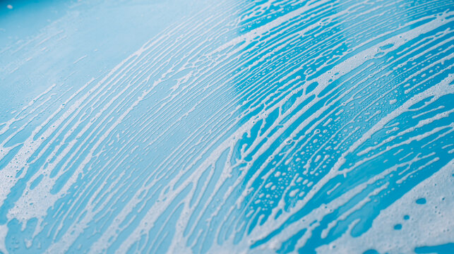 Fine diagonal cleaning foam lines covering a blue surface in close view.