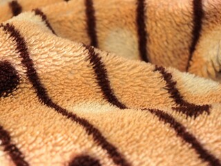 Brown and beige striped plush fabric texture with soft waves. © Fauzi