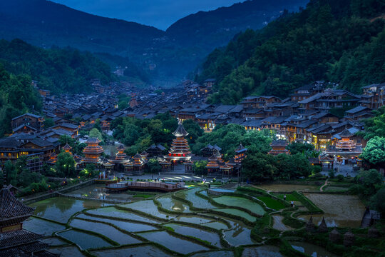 Miao village in the valley at blue hour with glowing lights, Xijiang, Guizhou, China