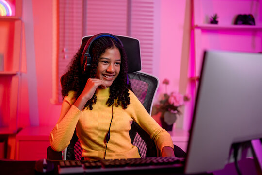 African American teenage girl playing online video game on computer.