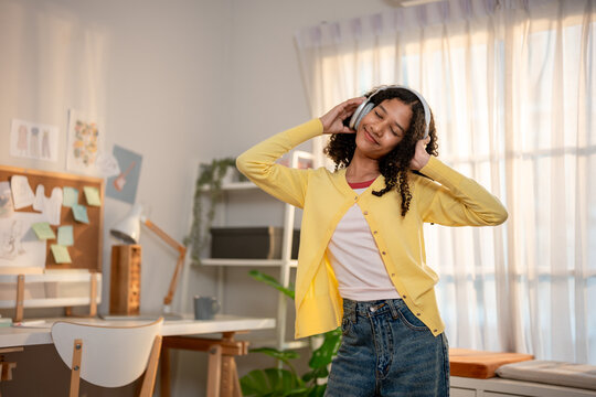African American teenage girl wearing headphones and dancing with music.