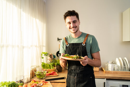 Portrait of Latino man wearing kitchen apron, preparing fresh salad.