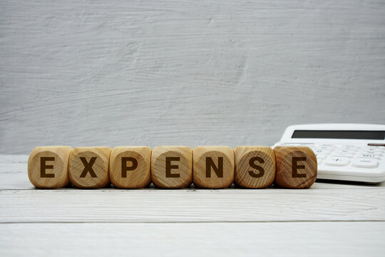 EXPENSE alphabet letters with calculator on wooden background